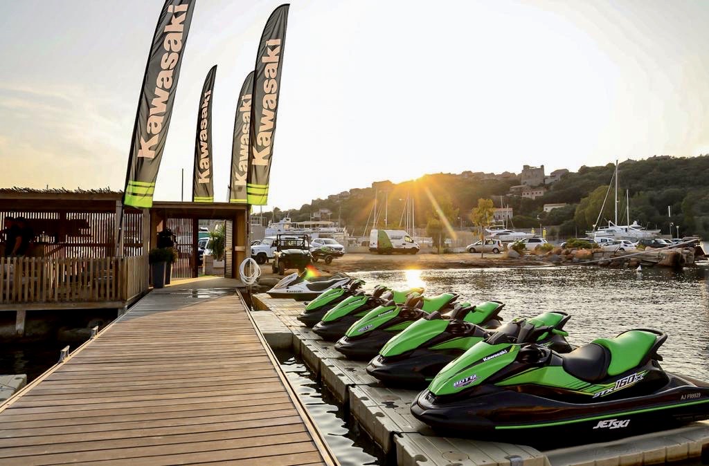 A gauche, ponton en bois menant au bureau d'accueil de Botti Racing sur le Port de Plaisance de Porto-Vecchio, et sur la droite, 6 jet-skis et le parking et la vue sur la haute-ville en arrière-plan